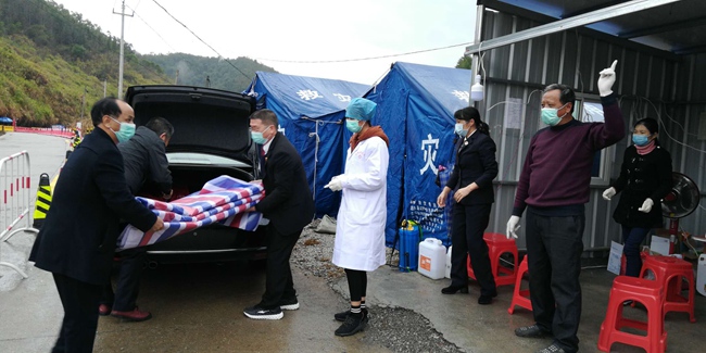 因下暴雨，盧永森（左一）找來了帆布，給卡點裡的黨員干部遮風避雨。