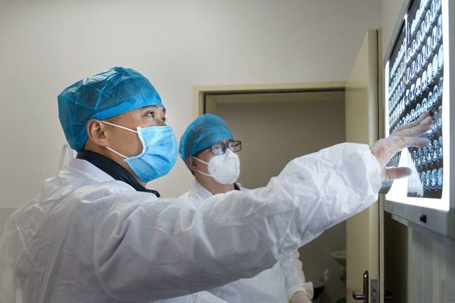 林孟新（前）在看疑似患者CT報告。 張文慶 攝