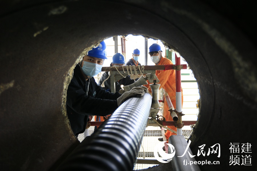 福建送變電公司施工人員將電纜送入平潭海峽公鐵大橋橋腹箱涵內。
