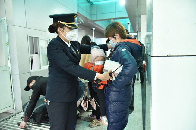 過安檢時，福州火車站值班站長趙靜為曹女士背上挎包。江曲攝