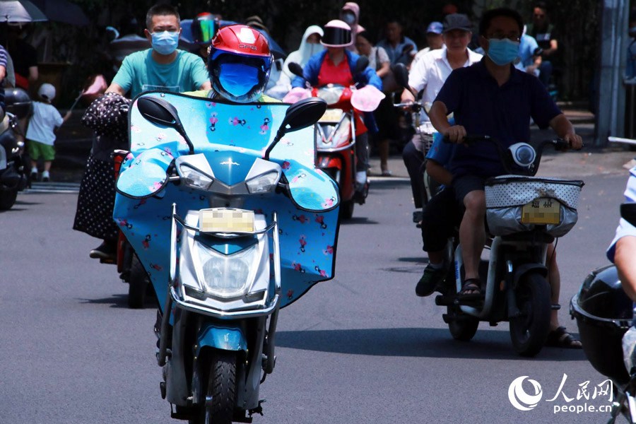 高溫天氣下，頭盔和口罩成為防晒“神器”。人民網 劉卿攝