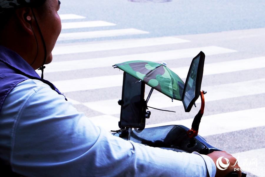 市民出行不僅自己做好防晒措施，還給手機“打遮陽傘”。人民網 劉卿攝