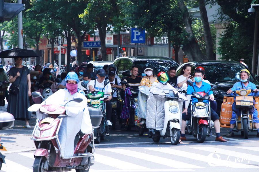 十字路口等紅燈間隙，市民在樹蔭下短暫乘涼。人民網 劉卿攝