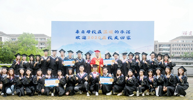 畢業典禮結束后，2020屆的校友們邀請院長張華榮在主題背景牆前合影。楊競雯攝