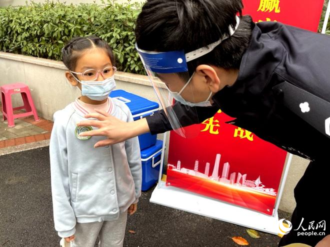福州一核酸采样点，现场工作人员为小朋友贴上核酸检测贴纸。人民网 陈蓝燕摄