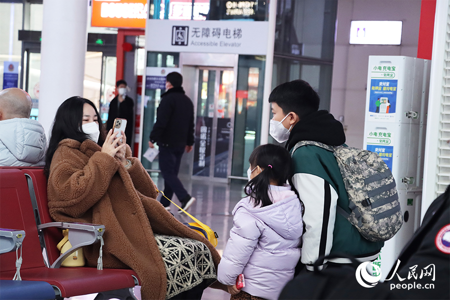 候车厅里,等车间隙,妈妈给两个孩子拍照。人民网 刘卿摄