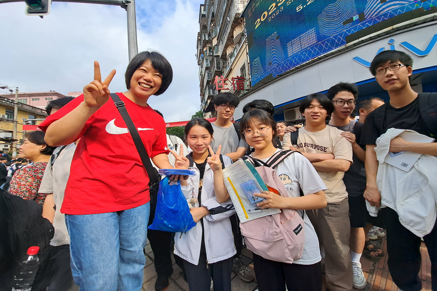13.在邵武一中考点外，一位老师正在给孩子们发准考证，进场前师生元气满满，对高考充满信心。陈春花摄