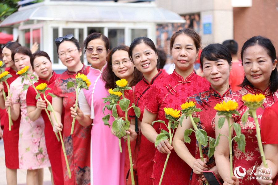4.厦门双十中学考生家长们身穿旗袍，手拿向日葵在考场外为孩子加油打气，寓意“旗开得胜，一举夺魁”。人民网记者 陈博摄