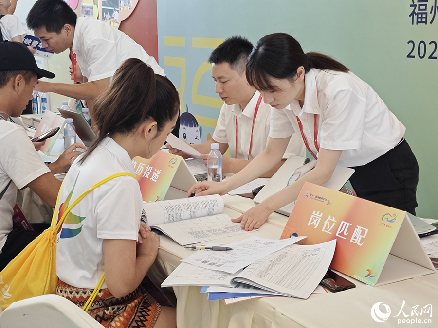 8月10日,“好年华·聚福州”2023年闽台青年人才研学营招聘会现场,一位台湾青年正在工作人员的协助下挑选适合自己的岗位。人民网 黄东仪摄