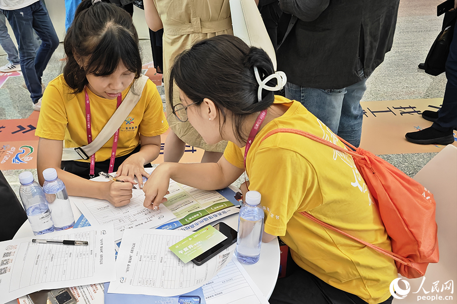 8月10日,“好年华·聚福州”2023年闽台青年人才研学营招聘会现场,两位台湾青年正填写求职材料。人民网 黄东仪摄