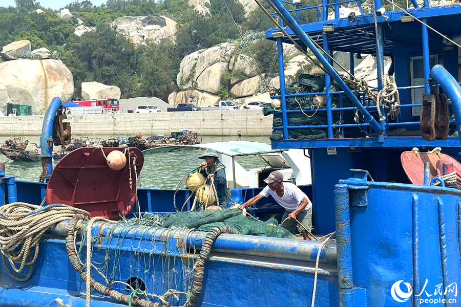 渔民钟文华与同伴整理渔网。人民网记者 林盈摄