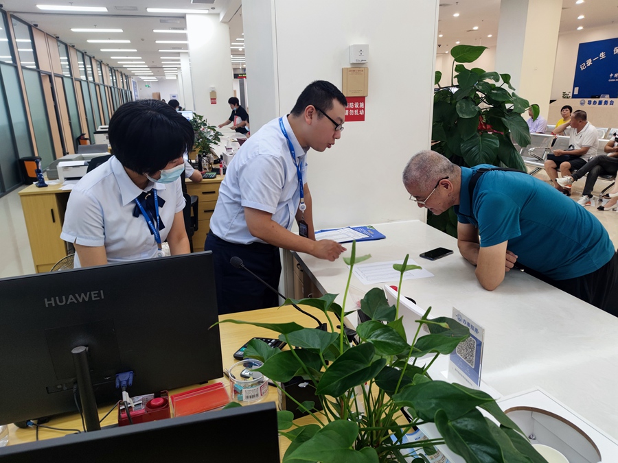 漳州市人社局社保窗口人员为办事老人耐心讲解社保业务办理流程。