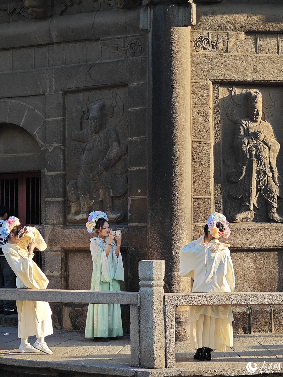 2024年1月18日，头戴“簪花”的游客们在开元寺镇国塔下拍照留念。人民网 黄东仪摄