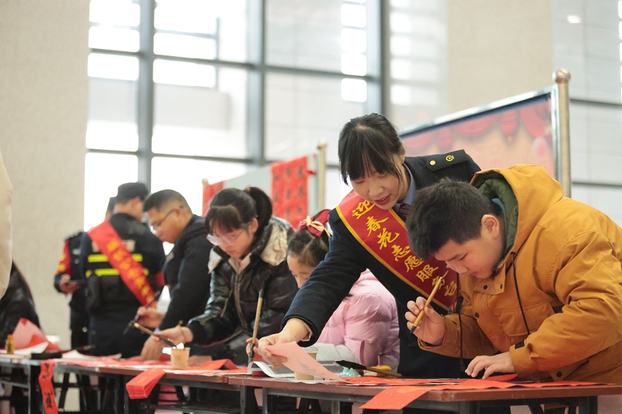 1月26日，铁路迎春花志愿服务台工作人员协助小旅客手写春联送福，传递满满年味。 张海根摄