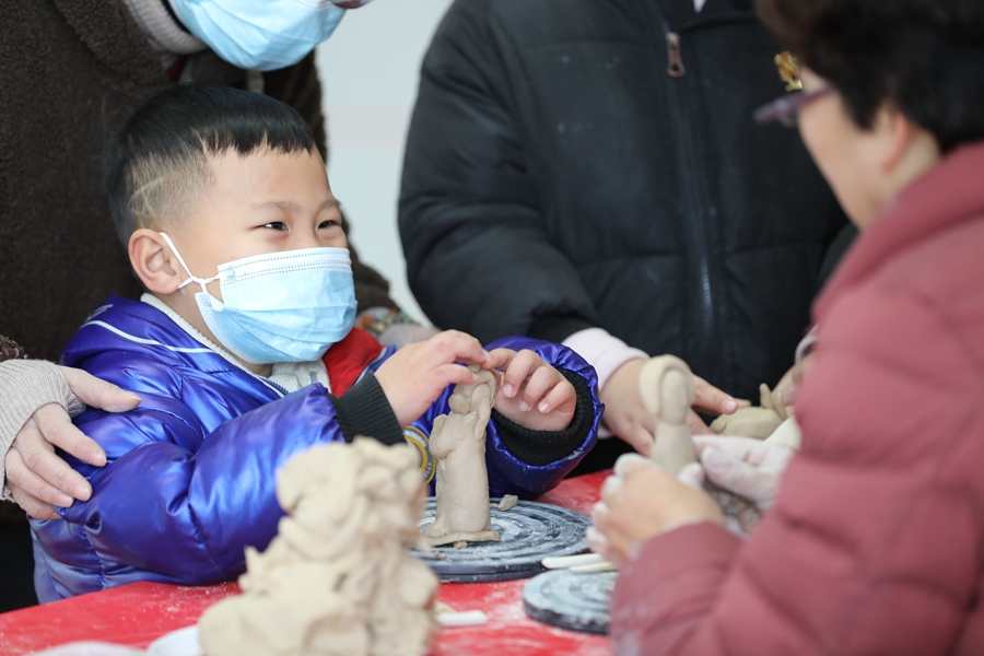 在泉州南站的“非遗集市”上，小旅客好奇地体验佛像雕塑工艺。邹阳摄