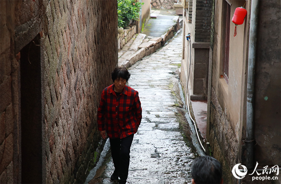 古城居民行走在梅花古城西施弄的石板路上，这条小巷的历史可追溯到明代。人民网 黄东仪摄