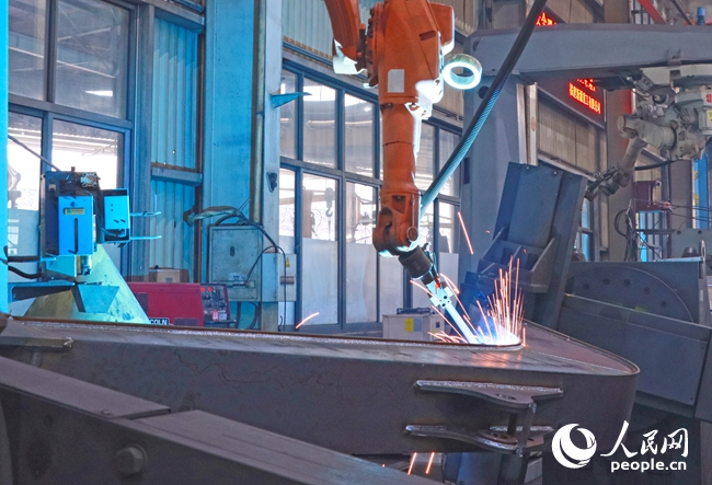 在自动化焊接的工作区域内，机械臂焊接系统精准地操作着。人民网 李昌乾摄