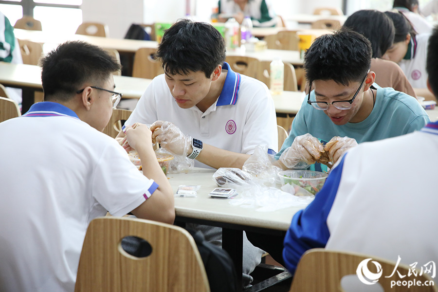 宽敞明亮的食堂内，同学们三五成群品尝美食。人民网 黄东仪摄