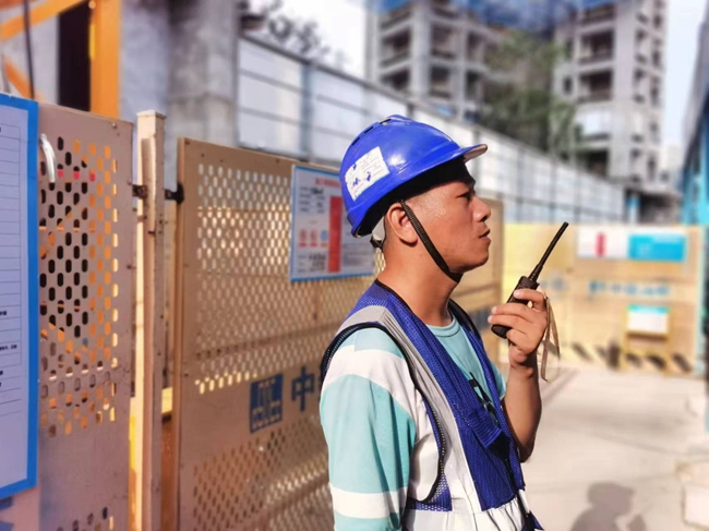 厦门市湖里区2023P07地块主体工程项目一线建设者正用对讲机指挥吊运材料。中建海峡厦门公司供图