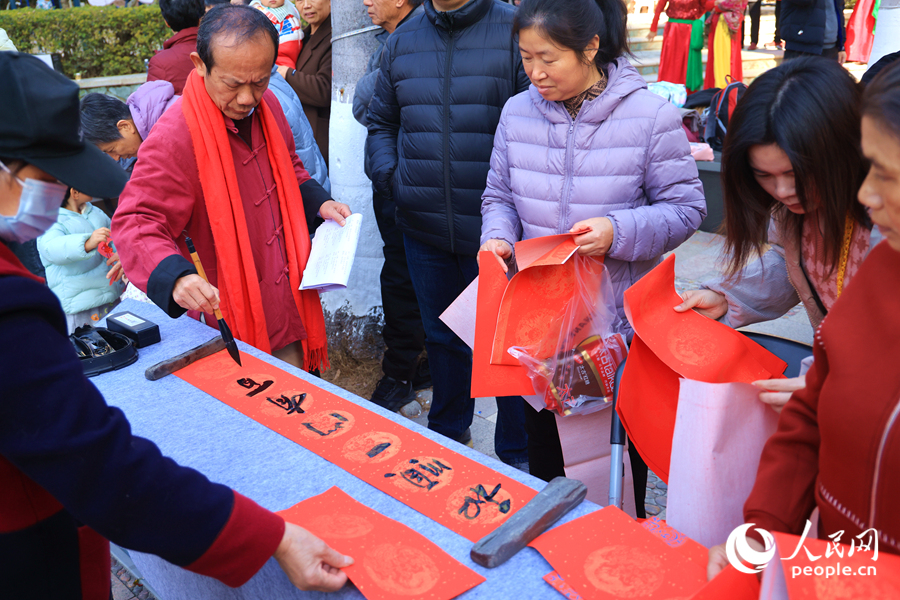 居民们纷纷自备红纸，排队领取郑先生写的“定制”版春联。人民网记者 陈博摄