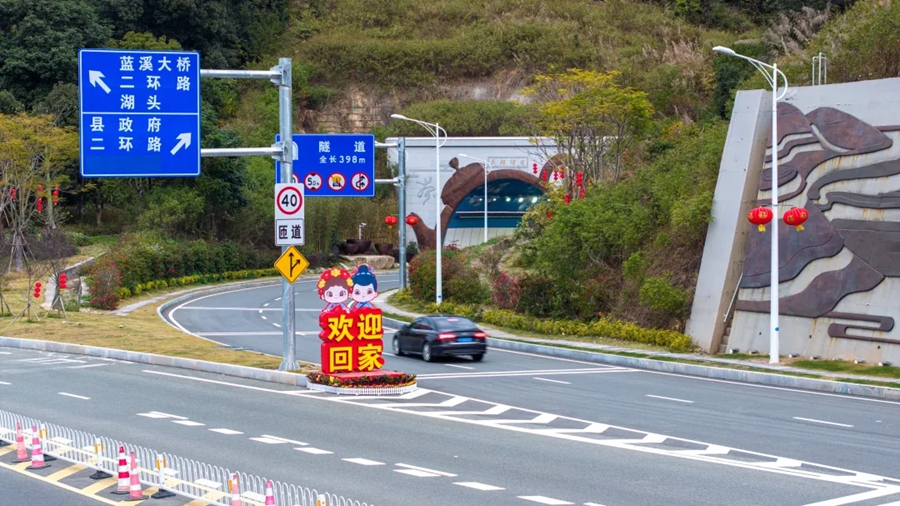 凤翔隧道入口前的人形立牌上写着“欢迎回家”