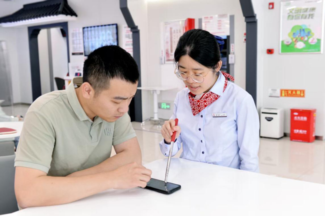 工作人员帮助客户在手机上办理业务。工行福州分行供图