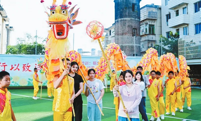 營員們在龍岩學院附屬小學與學生一同舞龍。龍岩市融媒體中心供圖