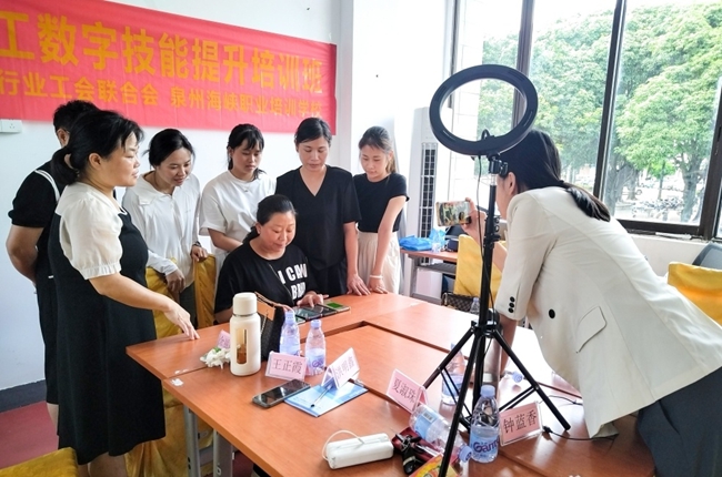 2025年家政女职工数字技能培训班现场，学员们围在一起学习如何操作直播间后台。泉州市家政行业工会联合会供图