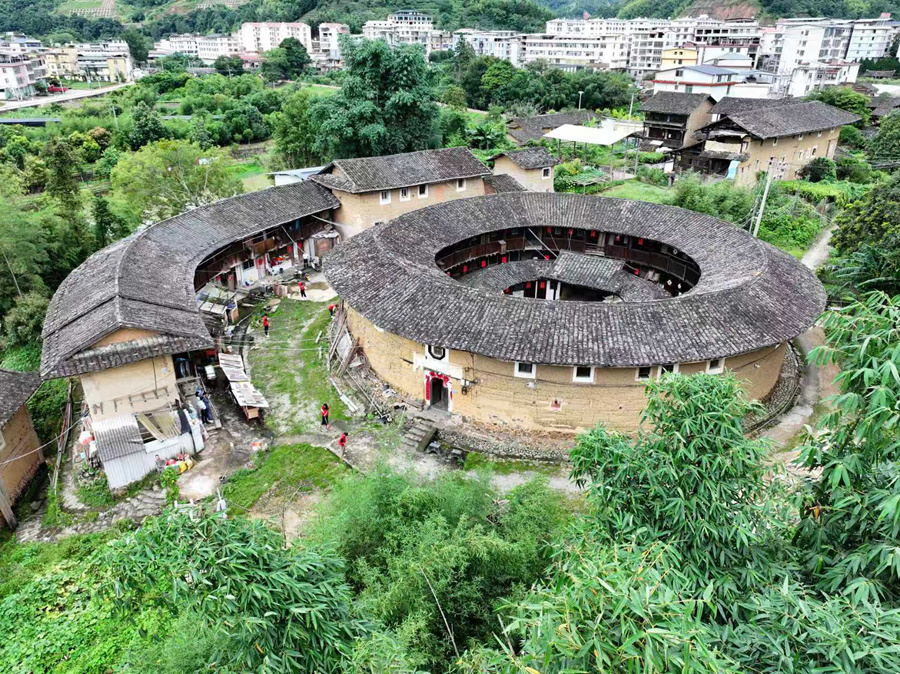 在书洋镇鹅冠楼前，身着红色马甲的文明实践队开展人居环境整治。南靖县融媒体中心供图