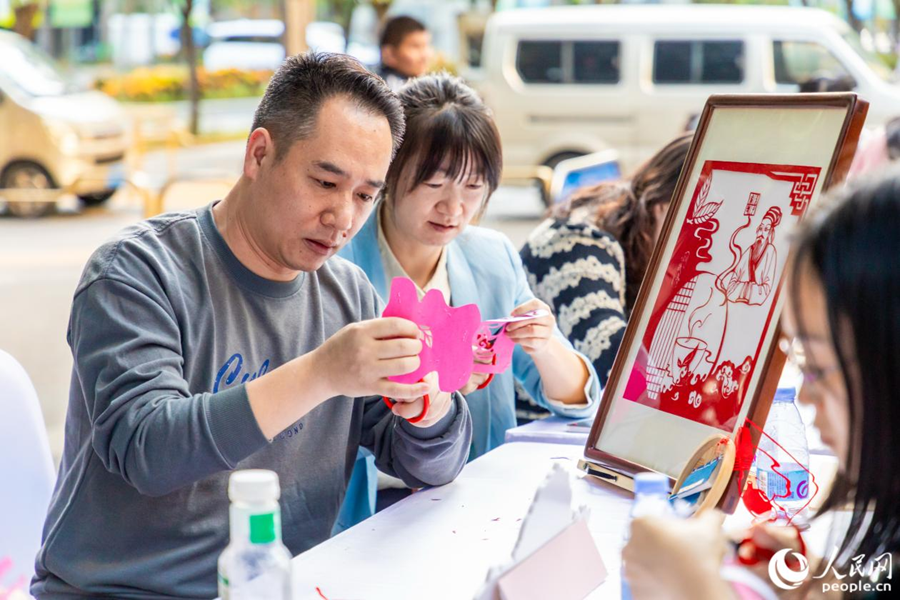 市民在戶外雅集區體驗剪紙。人民網攝