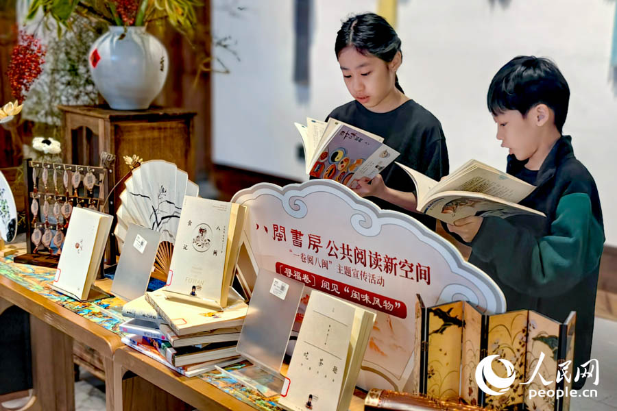 兩位來自新加坡的小朋友饒有興趣地翻看起介紹福州的書籍。人民網記者 葉青卿攝