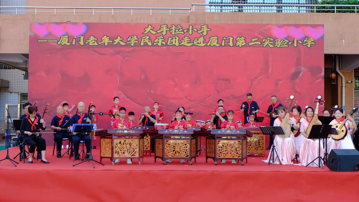 2025年“六一”前夕，厦门老年大学民乐团走进厦门第二实验小学开展“大手拉小手”关爱活动。