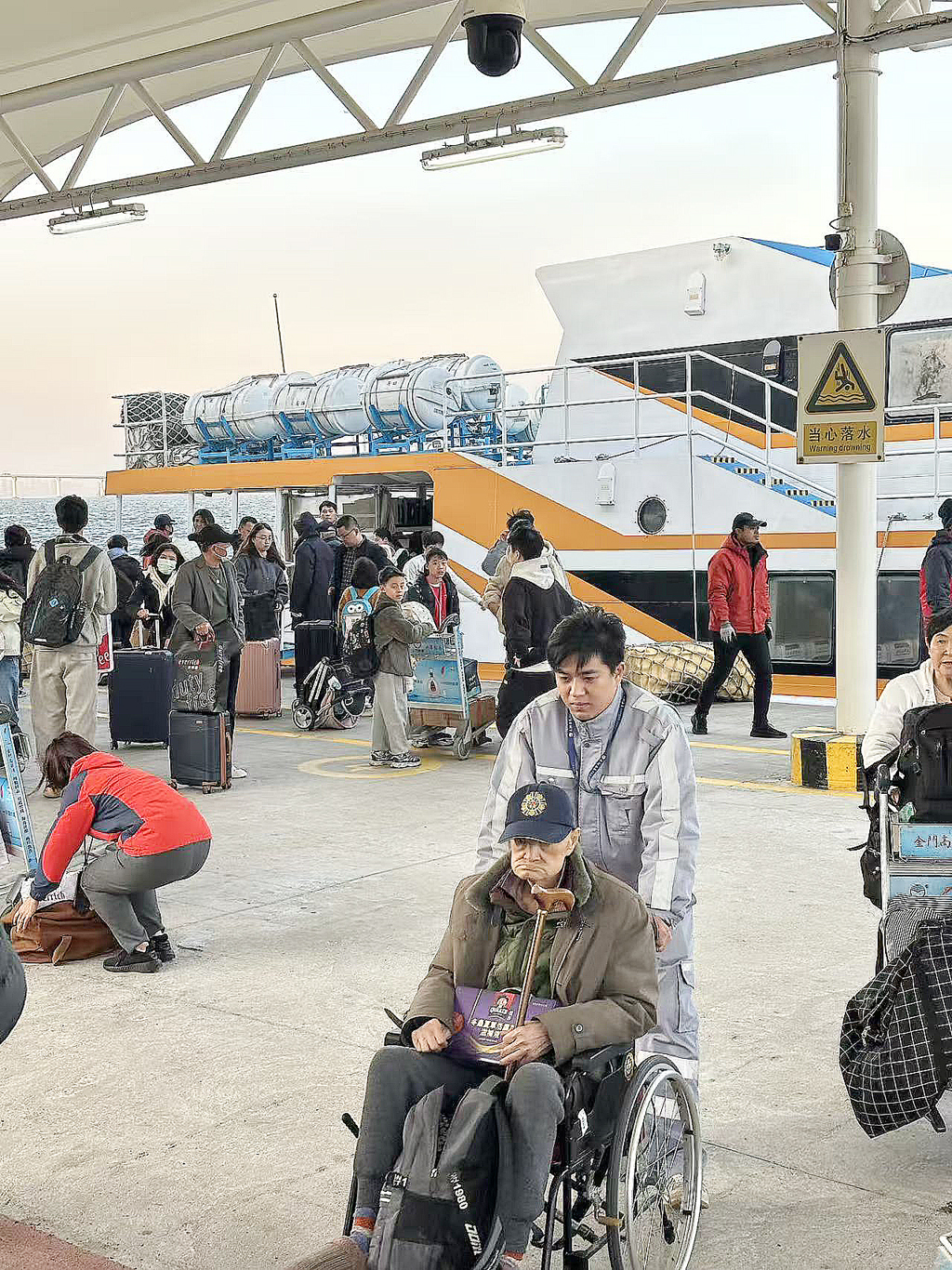 乘坐馬可波羅1號客船旅客，船停后碼頭工作人員用輪車協助行動不便的旅客。吳榕城攝