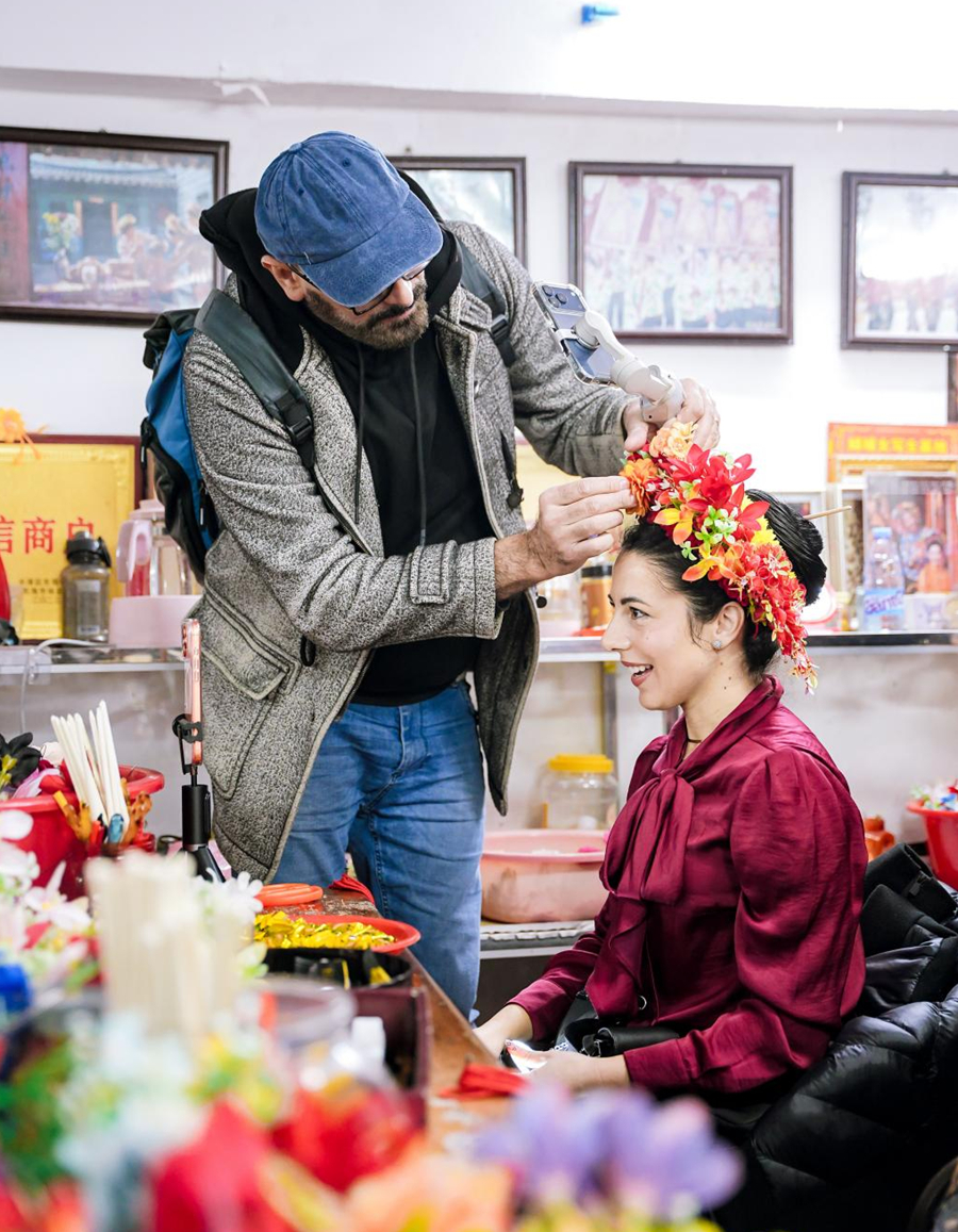 来自欧洲的旅游达人在梳妆台前佩戴“簪花围”，感受独特习俗。卢臻摄