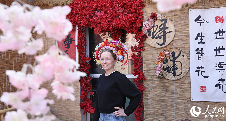 旅游达人头戴簪花围，笑立花门前。人民网记者 李昌乾摄