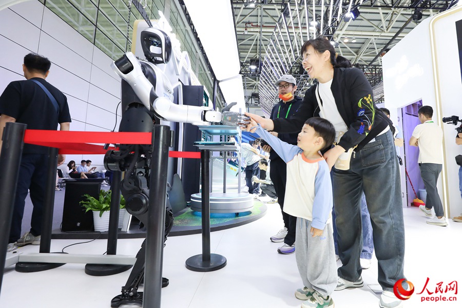 第八屆數字中國建設峰會上，小朋友和機器人互動握手。人民網記者 陳永整攝