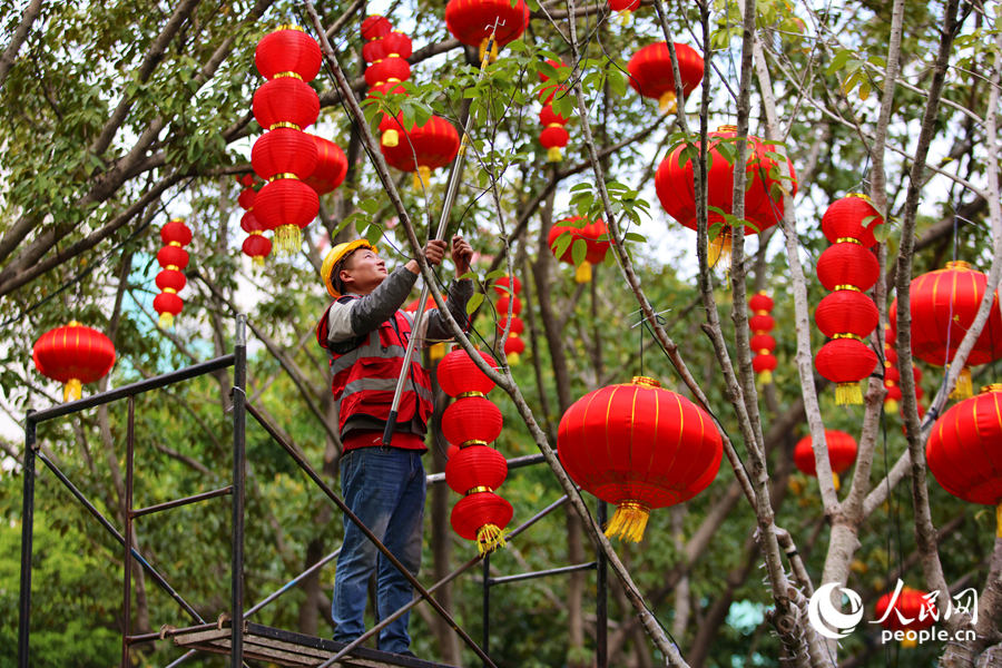 工人爬上腳手架，將一串串喜慶的燈籠安裝到位。人民網記者 陳博攝