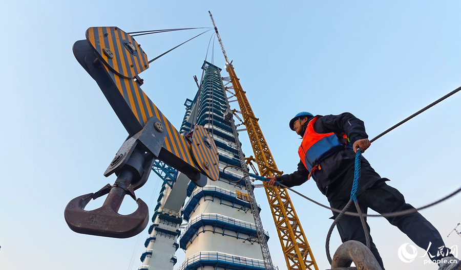 建設者正配合塔吊吊裝作業。人民網記者 李昌乾攝
