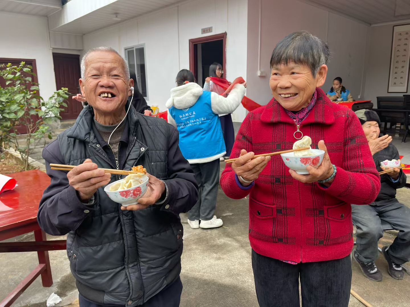 志愿者招呼村民一起品尝饺子