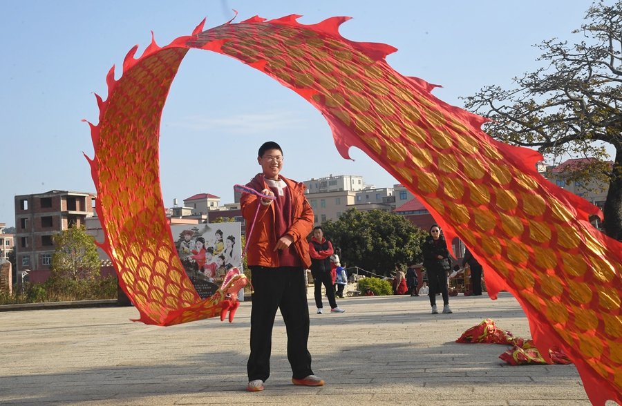在泉港區后龍鎮涂坑古民居百萬大厝前廣場，游客正在體驗舞彩帶龍