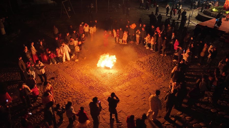 春节假期夜晚，游客在南门广场的篝火旁载歌载舞