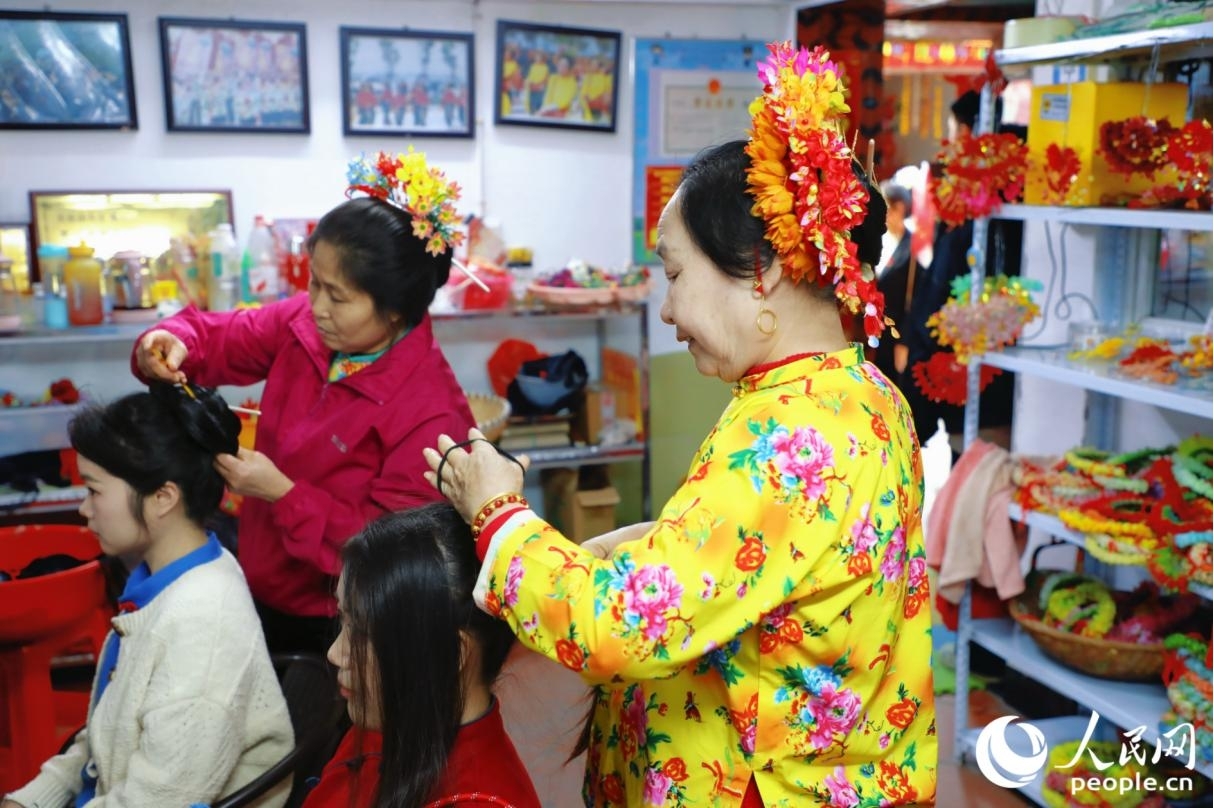 在福建省泉州市蟳埔村,当地村民正在为游客簪花。人民网记者 李唯一摄