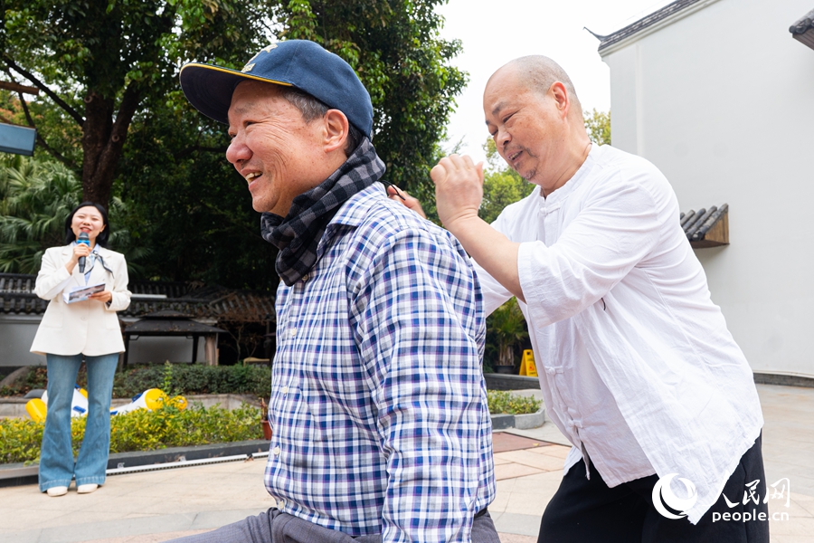 现场老人上台参与气功拍打互动，疏通经络、活络筋骨。实习生 李雨泽摄