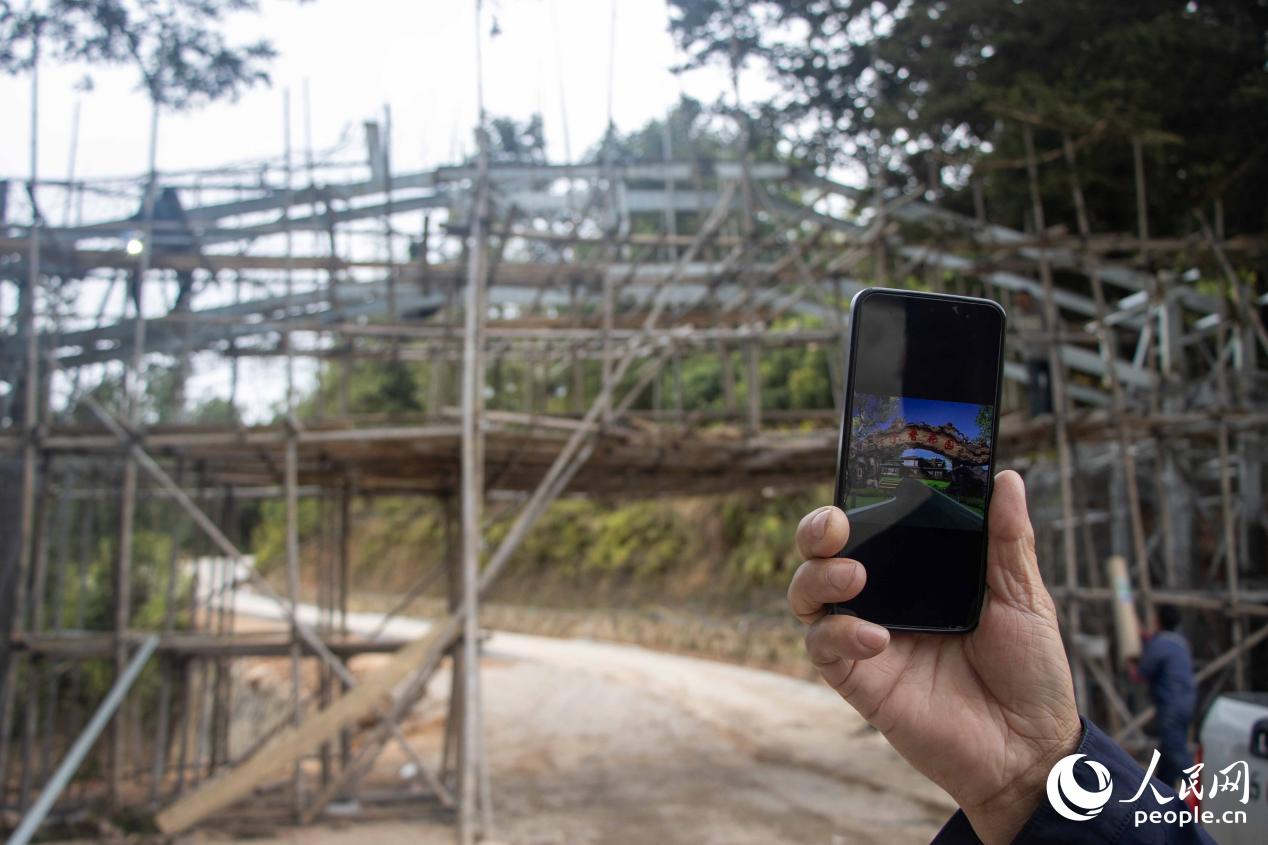景区入口处，一位村民股东向记者展示效果图。人民网 林铭贤摄