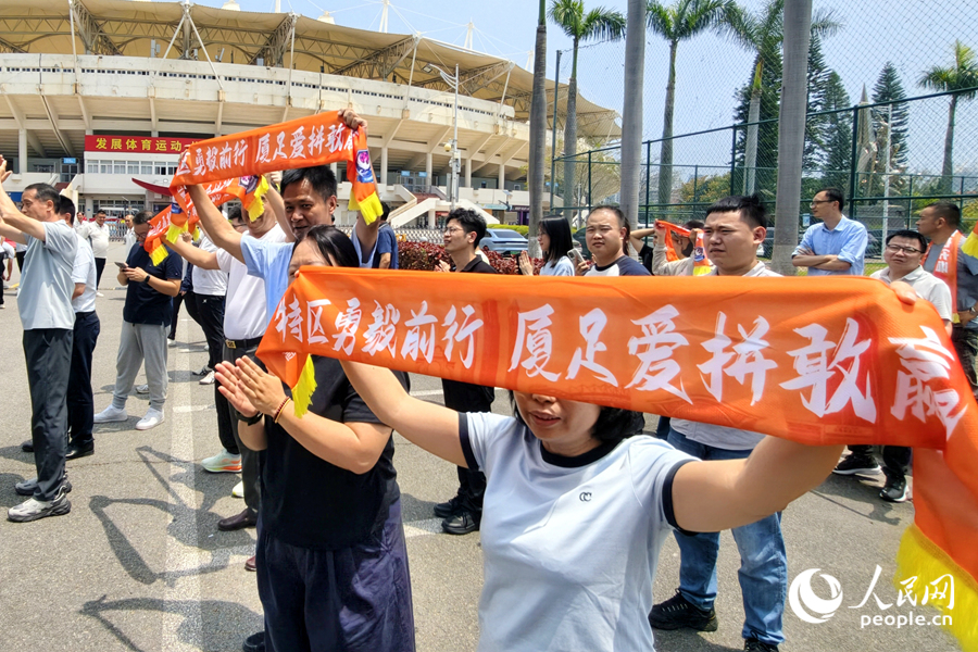 球迷们将印有“特区勇毅前行，厦足爱拼敢赢”标语的围巾举过头顶，欢迎“将士”们凯旋。人民网记者 陈博摄