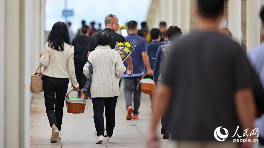 逝者家属手持鲜花寄托哀思，在工作人员的引导下有序登船。人民网记者 陈博摄