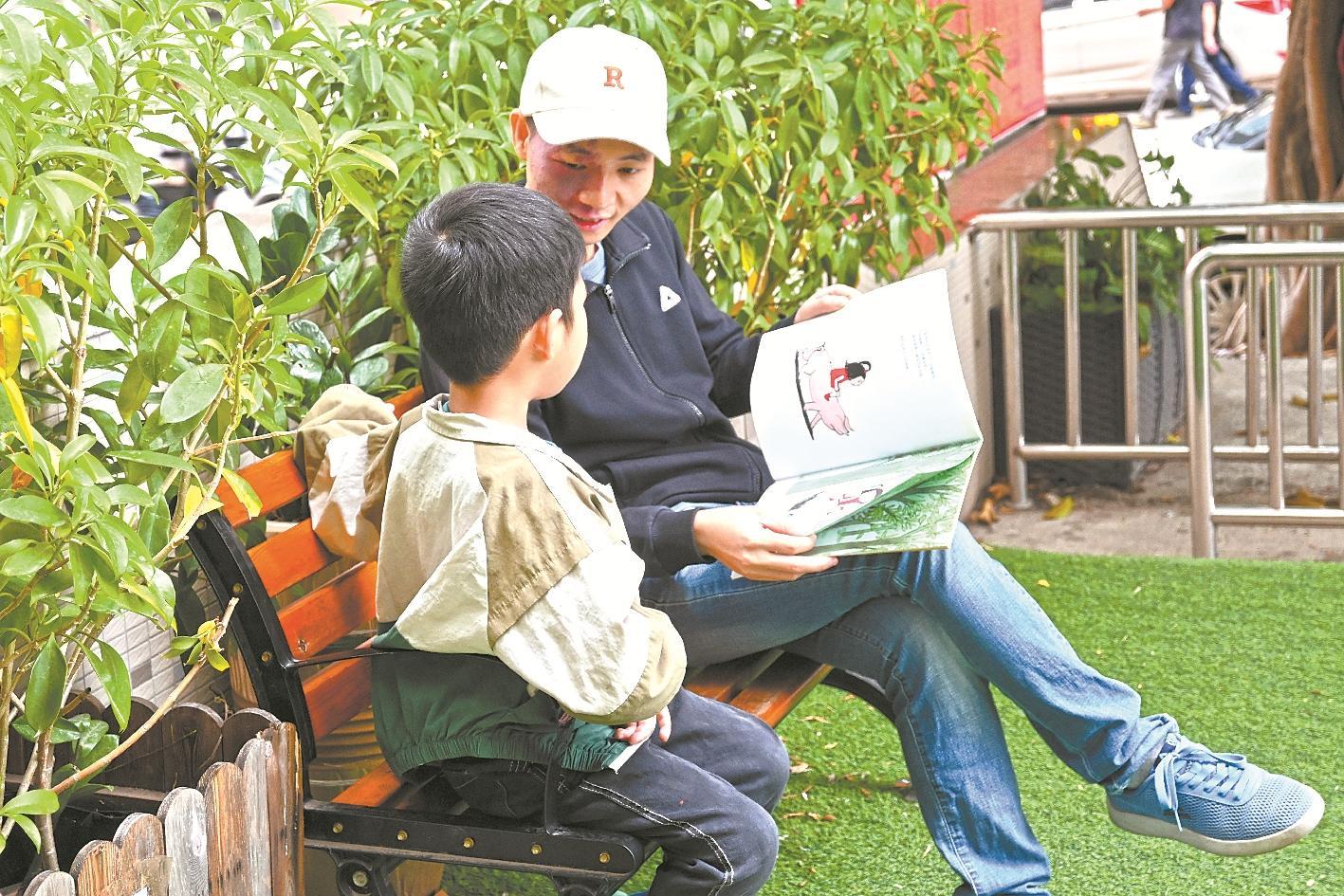 全国“乡村阅读推广人”苏佳斌在图书馆门口为乡村儿童讲绘本故事