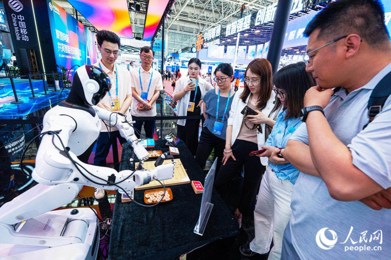 观众与中国移动展位上的机器人“切磋”棋技。实习生 李雨泽摄