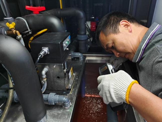 鑫叶公司技术人员佩戴手套精细调试管路阀门,于毫厘之间保障润版液供给稳定。颜荣摄