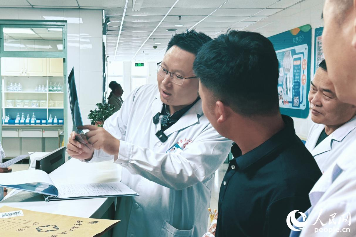 援宁医生郑鹏翔(左一)向患者分析病情。人民网记者 李唯一摄